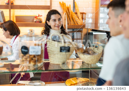 Young woman giving pastry to customer in cafe Young woman giving pastry to customer in cafe 136139843