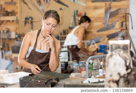 Young girl viewing interestedly taller mold in workshop Young girl viewing interestedly taller mold in workshop 136139864