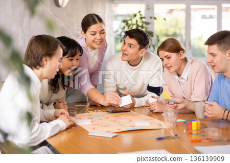 Smiling girls and boys play board games in classroom Smiling girls and boys play board games in classroom 136139909