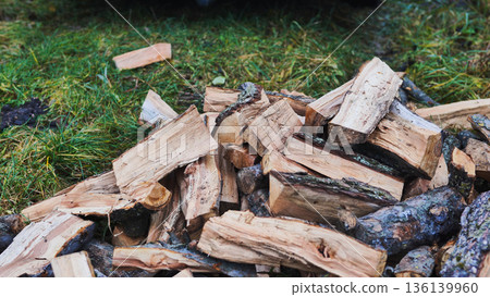 Pile of firewood logs on grass, preparing for winter 136139960