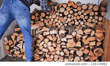 A man unloads firewood from a truck by hand. 136139962
