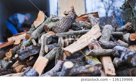 A man unloads firewood from a truck by hand. 136139966
