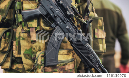 Soldier wearing camouflage vest holding a modern ak-47 assault rifle Soldier wearing camouflage vest holding a modern ak-47 assault rifle 136139978