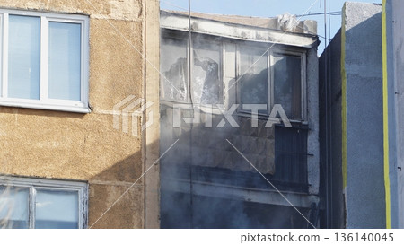 Smoke billowing from windows of apartment building during fire 136140045