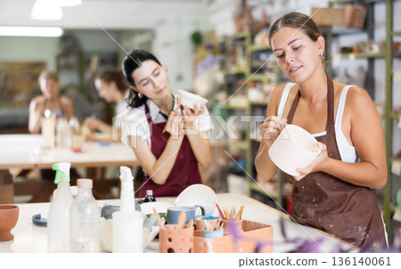 Girls processing clay bowls in carpentry workshop Girls processing clay bowls in carpentry workshop 136140061