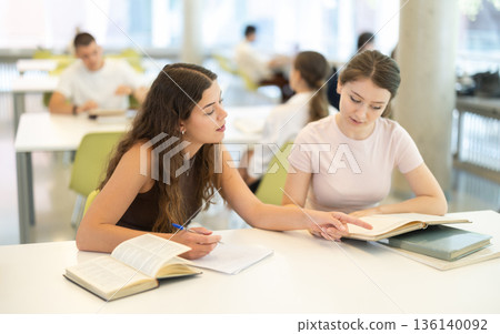 Women students study together in the library Women students study together in the library 136140092