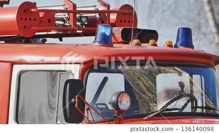 Red fire truck with blue flashing light on roof standing by for emergency response Red fire truck with blue flashing light on roof standing by for emergency response 136140098