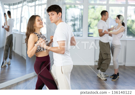 Dance training in group - young men and women dance salsa or bachata in dance studio Dance training in group - young men and women dance salsa or bachata in dance studio 136140122