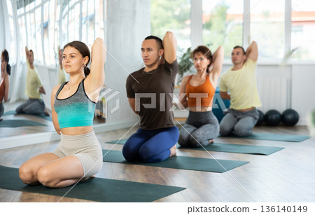 Lovers of active lifestyle on yoga mat perform doing diamond pose, vajrasana in gym Lovers of active lifestyle on yoga mat perform doing diamond pose, vajrasana in gym 136140149