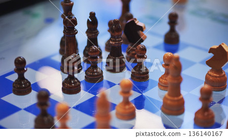 Wooden chess pieces standing on blue and white chessboard during a chess game 136140167