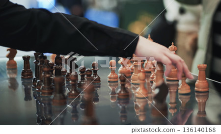 Wooden chess pieces standing on a reflective surface during a chess game 136140168