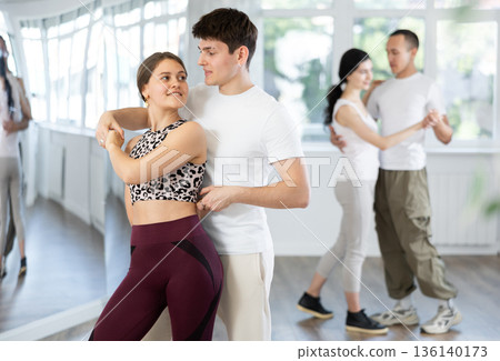 Girl paired up with young man, they train to perform slow waltz dance, rehearse performance. Girl paired up with young man, they train to perform slow waltz dance, rehearse performance. 136140173