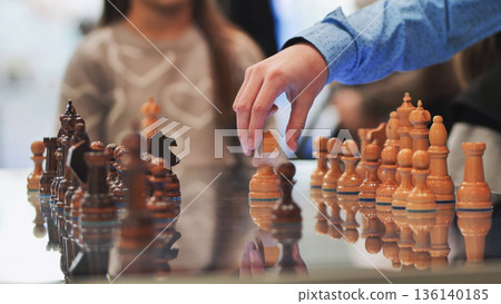 Hand moving a chess piece during a game, focusing on strategy and competition 136140185