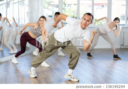 Young Asian man energizing group during dance fitness class Young Asian man energizing group during dance fitness class 136140204
