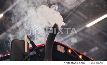 Exhaust pipe of a tractor emitting polluting smoke inside a shed Exhaust pipe of a tractor emitting polluting smoke inside a shed 136140205