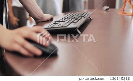 Person's hand using computer mouse, working on a desk in a modern office setup 136140218