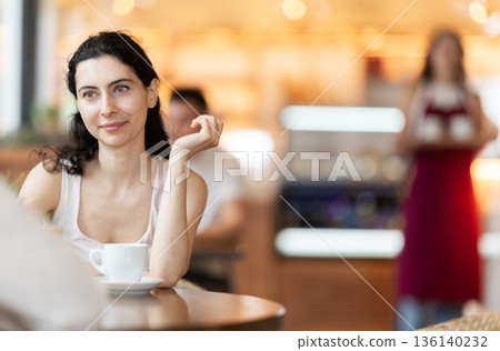 Girl in cafe sits opposite male companion, has nice conversation Girl in cafe sits opposite male companion, has nice conversation 136140232