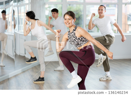 Smiling girl energizing group during dance fitness class 136140234