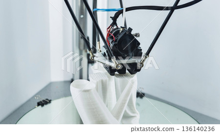 3D printer creating a white plastic prototype on a build platform 136140236