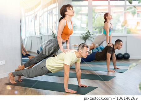Sports young woman and man doing acrobatics yoga poses, practicing acroyoga at gym 136140269