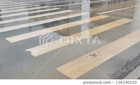 Pedestrian crossing on wet city street reflecting daylight during a rainy day 136140310