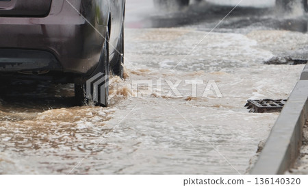 Car driving through flooded city street, wheels splashing water on a rainy day Car driving through flooded city street, wheels splashing water on a rainy day 136140320