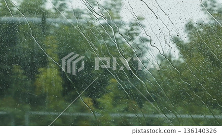 Rainwater streaming down window glass creating textured abstract background 136140326