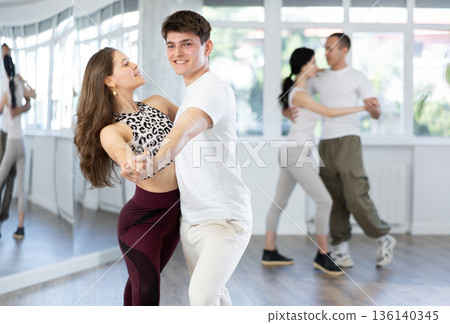 Young couple enjoying slow foxtrot in dance studio Young couple enjoying slow foxtrot in dance studio 136140345