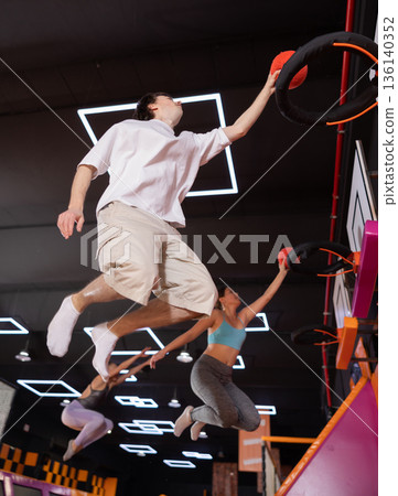 Young guy playing ball in trampoline center 136140352