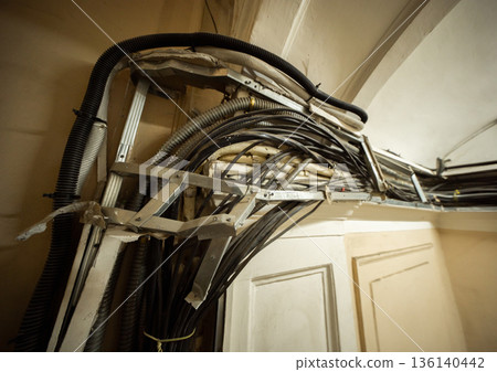 Tangled electrical wiring and cables creating a messy ceiling installation Tangled electrical wiring and cables creating a messy ceiling installation 136140442
