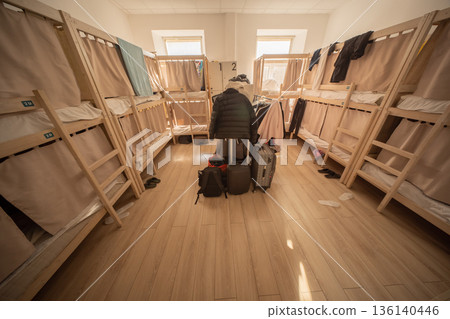 Modern hostel room interior showing wooden bunk beds with beige curtains and clothes hanging Modern hostel room interior showing wooden bunk beds with beige curtains and clothes hanging 136140446