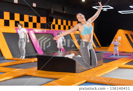 Young woman trains jumping in trampoline center Young woman trains jumping in trampoline center 136140451