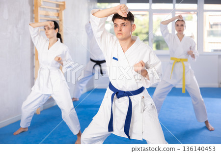 Fighting stance of men and women during group karate training in gym Fighting stance of men and women during group karate training in gym 136140453