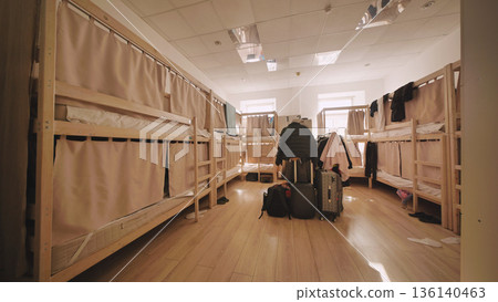 Hostel dormitory interior with empty bunk beds, suitcases, and privacy curtains Hostel dormitory interior with empty bunk beds, suitcases, and privacy curtains 136140463