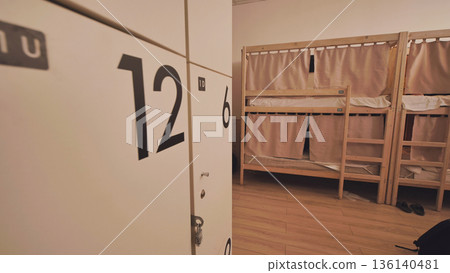 Hostel dormitory with bunk beds offering privacy curtains and personal lockers for travelers Hostel dormitory with bunk beds offering privacy curtains and personal lockers for travelers 136140481