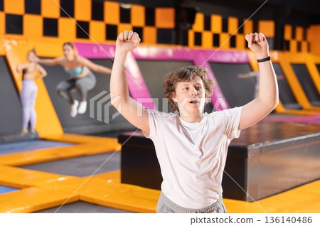 Portrait of joyful young teenager in sport clothes enjoying weekend time on trampolines in entertainment center 136140486