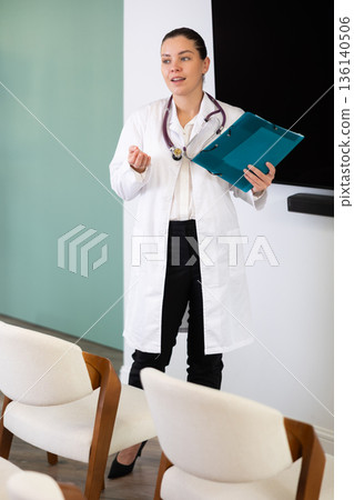 Female doctor giving a lecture with a folder in her hands 136140506