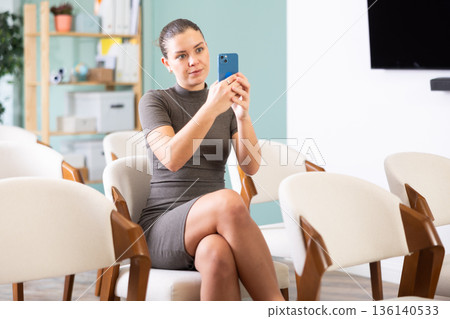 Young female student taking photo on smartphone at training 136140533