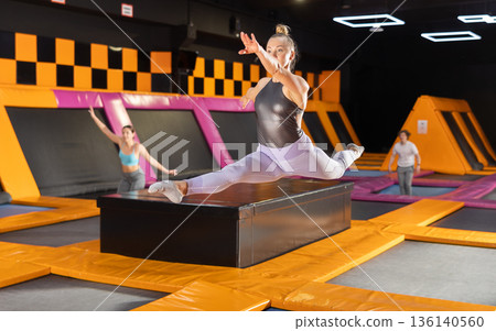 Emotive adult woman having great time while jumping on colorful trampoline in entertainment center 136140560