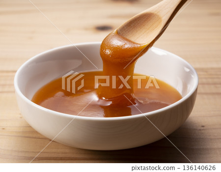 Rich Manuka honey scooped into a wooden spoon (close-up on a white background) Rich Manuka honey scooped into a wooden spoon (close-up on a white background) 136140626
