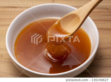 用木匙舀起濃鬱的麥盧卡蜂蜜（白色背景特寫） 136140627