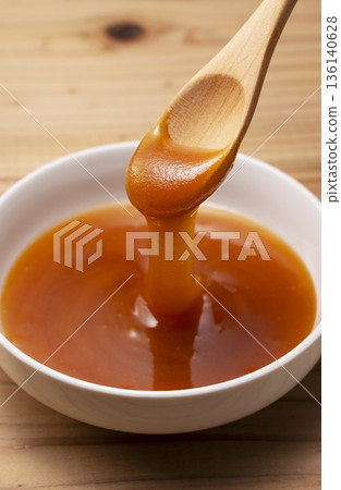 Rich Manuka honey scooped into a wooden spoon (close-up on a white background) 136140628