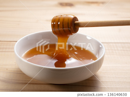 濃鬱的麥盧卡蜂蜜從蜂蜜勺中滴落（白色背景特寫） 136140630