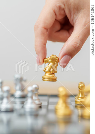hand moving gold Chess knight figure and Checkmate opponent during chessboard competition. Strategy, Success, management, business planning, win, disruption, Trade war and leadership concept hand moving gold Chess knight figure and Checkmate opponent during chessboard competition. Strategy, Success, management, business planning, win, disruption, Trade war and leadership concept 136141862