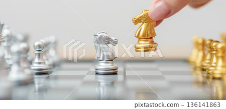 hand moving gold Chess knight figure and Checkmate opponent during chessboard competition. Strategy, Success, management, business planning, win, disruption, Trade war and leadership concept hand moving gold Chess knight figure and Checkmate opponent during chessboard competition. Strategy, Success, management, business planning, win, disruption, Trade war and leadership concept 136141863
