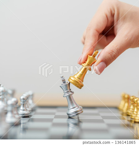 hand moving gold Chess King figure and Checkmate opponent during chessboard competition. Strategy, Success, management, business planning, win, disruption, Trade war and leadership concept 136141865
