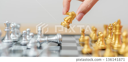 hand moving gold Chess knight figure and Checkmate opponent during chessboard competition. Strategy, Success, management, business planning, win, disruption, Trade war and leadership concept hand moving gold Chess knight figure and Checkmate opponent during chessboard competition. Strategy, Success, management, business planning, win, disruption, Trade war and leadership concept 136141871