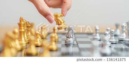 hand moving gold Chess knight figure and Checkmate opponent during chessboard competition. Strategy, Success, management, business planning, win, disruption, Trade war and leadership concept 136141875