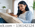 Smiling pretty young Asian woman sitting on cozy couch 136142124