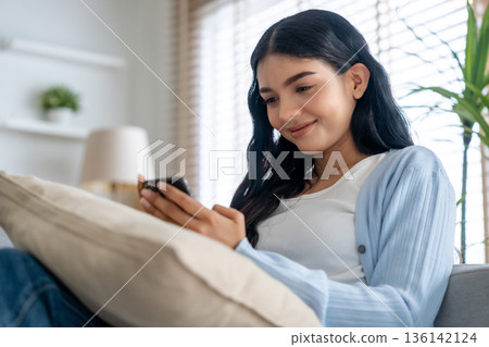 Smiling pretty young Asian woman sitting on cozy couch 136142124
